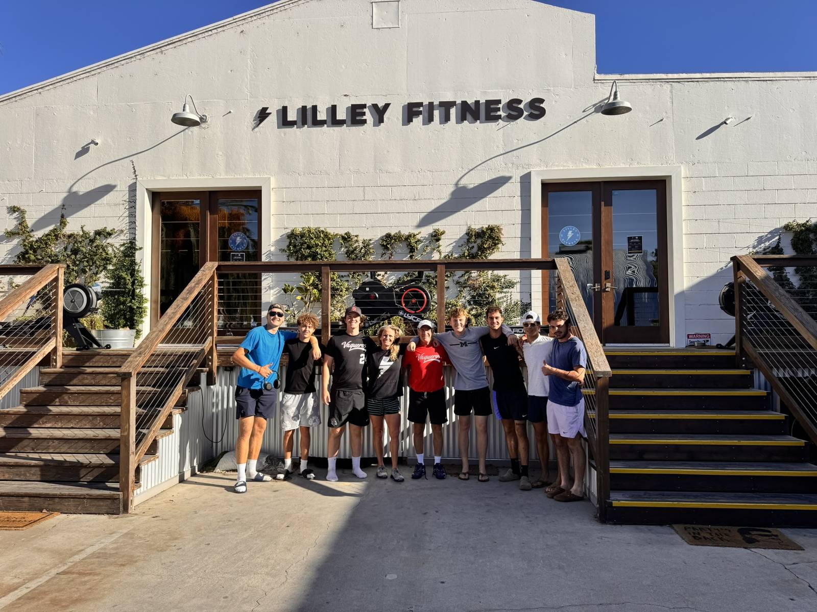 A group of young athletes with Erika Lilley outside the white Lilley Fitness building.